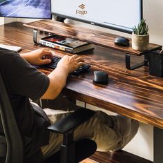 a person sitting at a desk with a keyboard and mouse in front of a monitor