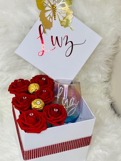 a white box with red roses and chocolates in it sitting on a furry surface