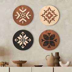 four circular wooden wall hangings on the wall in a room with vases and other items