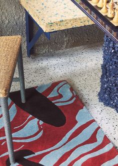 a table with chess pieces on it in front of a rug and chair next to the table