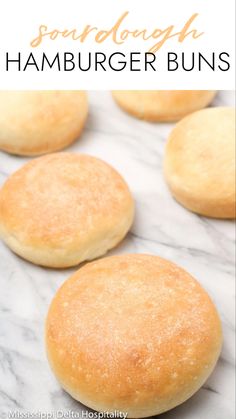 some bread buns are on a marble counter top with text overlay that reads sourdough hamburger buns