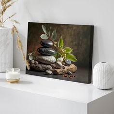 a white vase sitting on top of a table next to rocks and plants in it