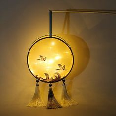 a lamp that has birds on it and tassels hanging from the side,