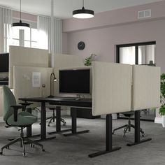 an office cubicle with three computer screens and two chairs