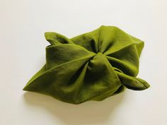 a close up of a green cloth on a white surface with a knot in the middle