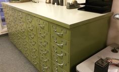 a green filing cabinet sitting next to a white counter top with lots of drawers on it