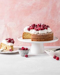 there is a cake with white frosting and raspberries on the plate next to it