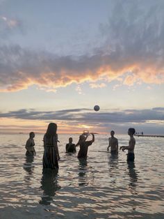 people are playing volleyball in the water at sunset