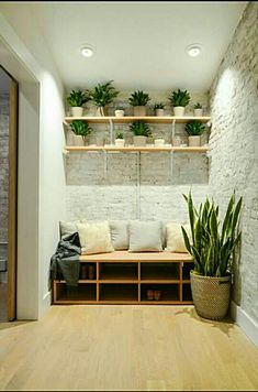 a living room filled with lots of plants on shelves next to a wooden floor and white brick wall