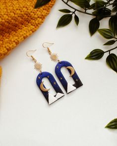 a pair of earrings sitting on top of a white table next to a potted plant