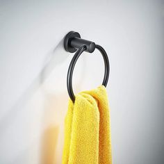 a yellow towel hanging on the wall next to a black metal holder with a hook