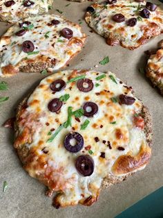 several pizzas with olives and cheese on top