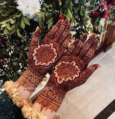 a woman's hands with hennap on it and flowers in the background