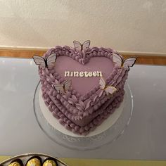 a heart shaped cake sitting on top of a table next to some chocolates in a bowl