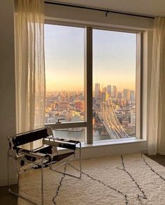 a chair sitting in front of a large window overlooking a cityscape and bridge