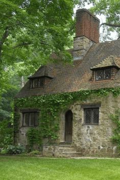 an old stone house with ivy growing all over it's roof and windows, surrounded by lush green trees