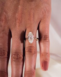 a woman's hand with a diamond ring on top of her left hand,