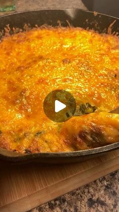 a casserole with cheese and green peppers in a pan on a wooden cutting board