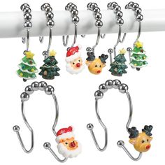 six christmas themed hooks hang on a white curtain rod with silver balls attached to them