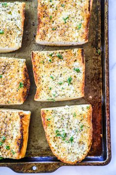 square pieces of bread with cheese and herbs on top in a baking pan, ready to be baked