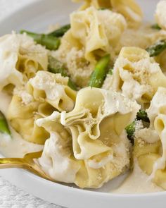 a bowl filled with pasta and asparagus on top of a white table cloth