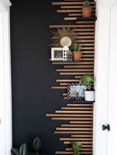 a black wall with wooden slats on it and some potted plants in the corner