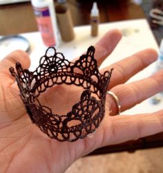 a hand is holding a black lace ring