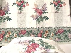 a white bed with floral bedspread and matching pillow cases in front of a window