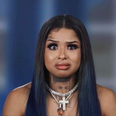 a woman with blue hair and piercings on her face is looking at the camera