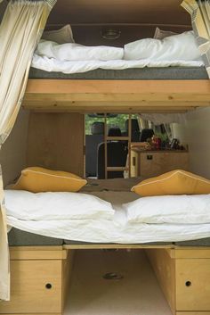 bunk beds are built into the side of a van with curtains on each side and two drawers under them