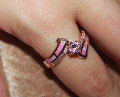 a close up of a person's hand with a pink ring on their finger