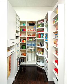 an organized pantry with white shelves and wood flooring