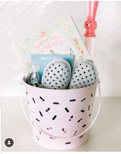 a pink bucket filled with lots of items on top of a white table next to a red toothbrush