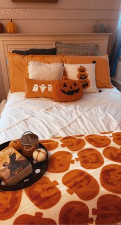 a bed with an orange and white bedspread, two pumpkins on the pillow