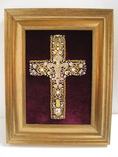 an ornate cross is framed in a gold frame with purple velvet and pearls on it