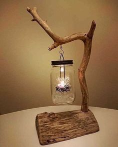 a glass jar with a candle inside sitting on top of a piece of driftwood