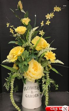 a white vase with yellow flowers and greenery on the bottom that says flowers & garden