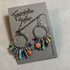 a pair of earrings with colorful beads and charms hanging from it's earwires