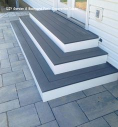 three steps leading up to the front door of a white house with black and gray trim