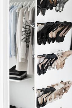 an organized closet with shoes and clothes hanging on the wall, including heels in black and white