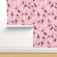 a pink wallpaper with black and white drawings on it, next to a wooden floor