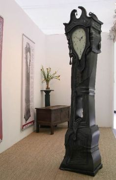 a tall black clock sitting in the middle of a room