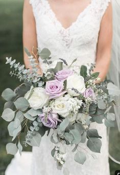 a bride holding a bouquet of flowers and greenery