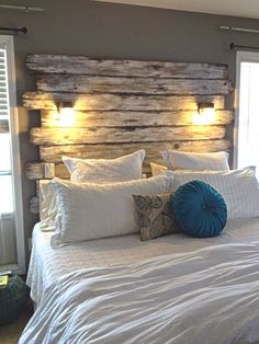 a bed with white sheets, pillows and wooden headboard made from pallet boards