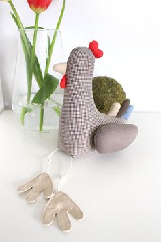 a stuffed bird sitting on top of a table next to a vase filled with tulips