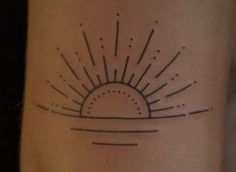 a sun tattoo on the arm that is black and white with lines coming out of it