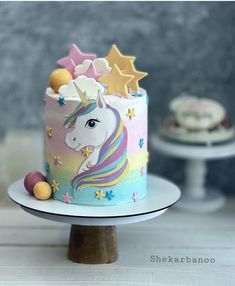 there is a cake decorated with stars and a unicorn on the top, next to two cupcakes