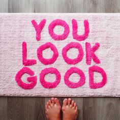 someone is standing on the floor in front of a pink rug that says you look good