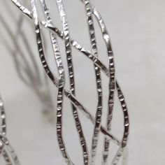 The ZusZa collection is characterized by its irregular braiding. To each wire we apply the typical surface of our workshop before welding and shaping. ZusZa is elegant and easy to wear on any occasion. We love hoops :) In our store we offer more than 100 different models. M A T E R I A L  Sterling Silver M E A S U R E M E N T S ZusZa hoops are made in 4 sizes. As each piece is completely handmade, there may be some small differences.  small: 12mm diameter, braided with 4 wires, maximum width 5mm, weight 2,3g medium: 25mm diameter,  braided with 6 wires, maximum width 10mm, weight 6,6g big: 30mm diameter,  braided with 4 wires, maximum width 6mm, weight 4,1g XL: 50mm diameter,  braided with 6 wires, maximum width 12mm, weight 8,5g F I N I S H E S Hammered Silver. Through the hammering the s Silver Hoop Earrings With A Modern Twist, Modern Twist Silver Hoop Jewelry, Elegant Braided Sterling Silver Jewelry, Modern Twist Silver Hammered Jewelry, Handmade Metal Jewelry With A Modern Twist, Sterling Silver Braided Jewelry In Silver, Sterling Silver Braided Silver Jewelry, Braided Sterling Silver Jewelry, Silver Jewelry With Interwoven Design As A Gift