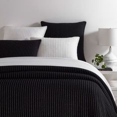 a bed with black and white striped comforter next to a lamp on a nightstand